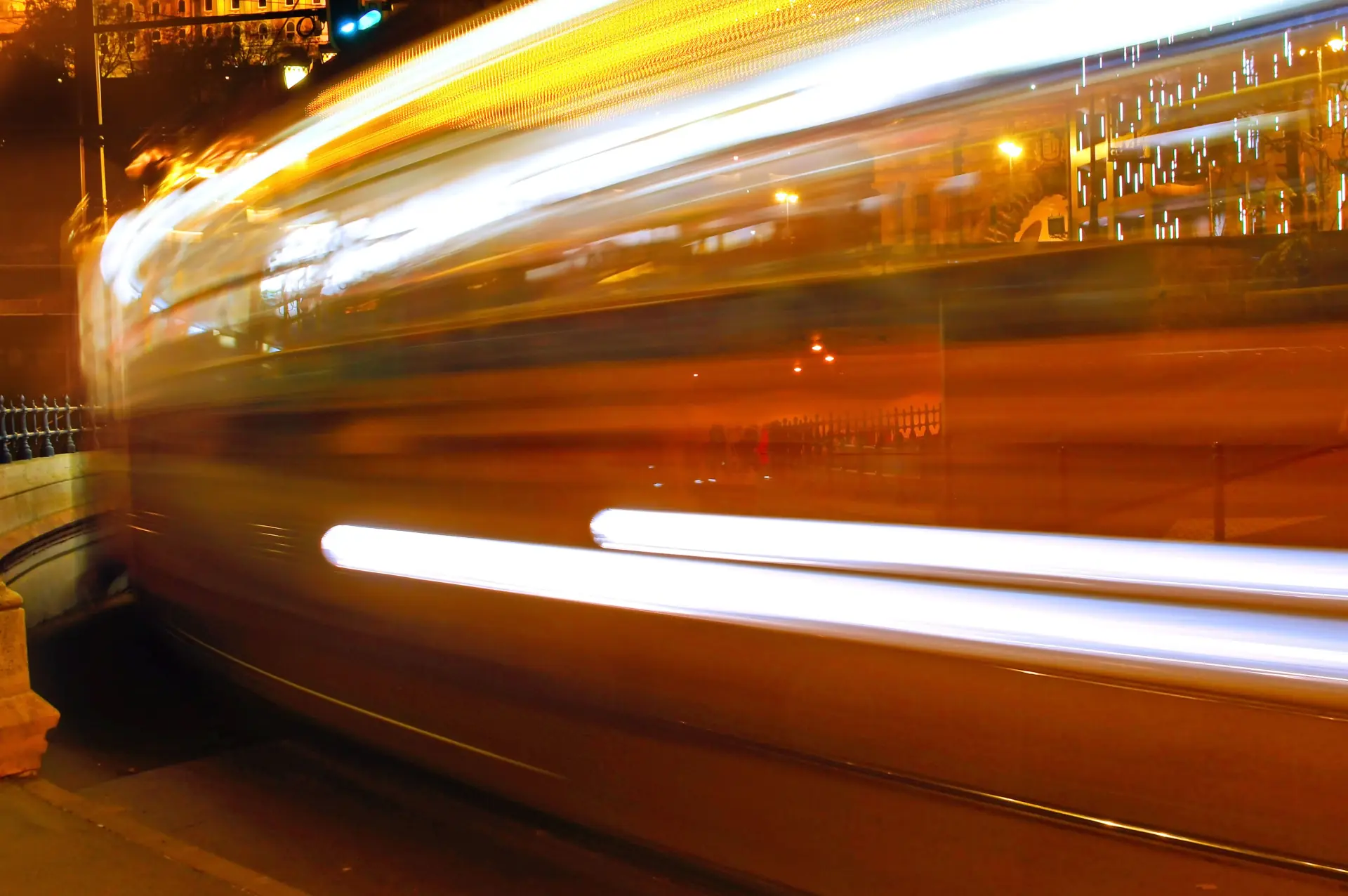 Long streaks of warm light from a passing vehicle blur across a dark street at night.